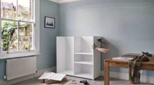 Flat-pack components for a tall storage cabinet for an office, laid out alongside an instruction manual for easy home assembly.
